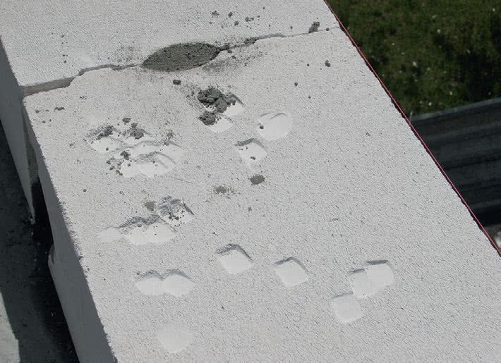 Złe użycie narzędzi. Młotek murarski uszkodził powierzchnię bloczków z betonu komórkowego Złe użycie narzędzi. Młotek murarski uszkodził powierzchnię bloczków z betonu komórkowego